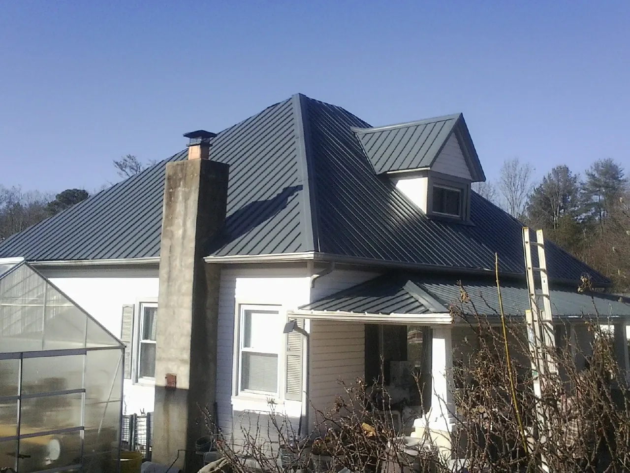 Dark blue standing seam metal roof on a white farmhouse with dormer — Slate & Tile Roof Repair by Roofing Brothers in Canyonville