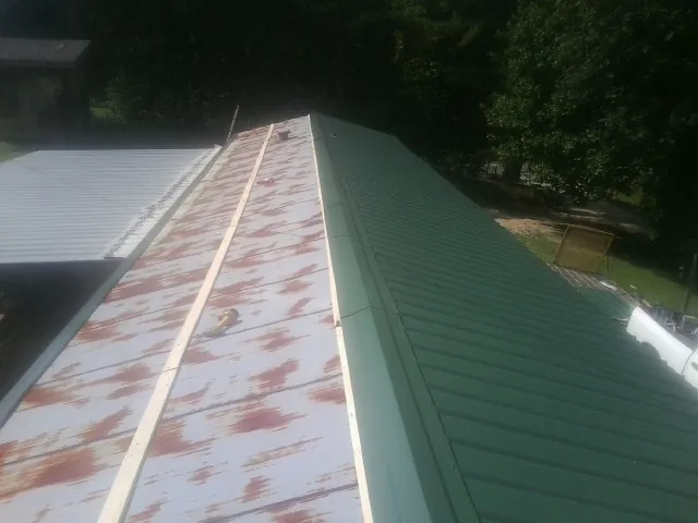 Old rusted panels beside newly installed green metal roofing — Wind Damage Roof Repair by Roofing Brothers in Canyonville