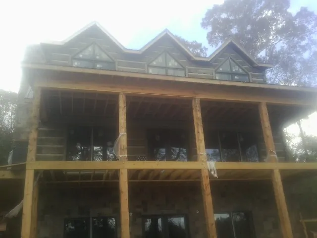 Dormers and porch framing on a large log home under construction — Roof Coating work by our crew in Canyonville