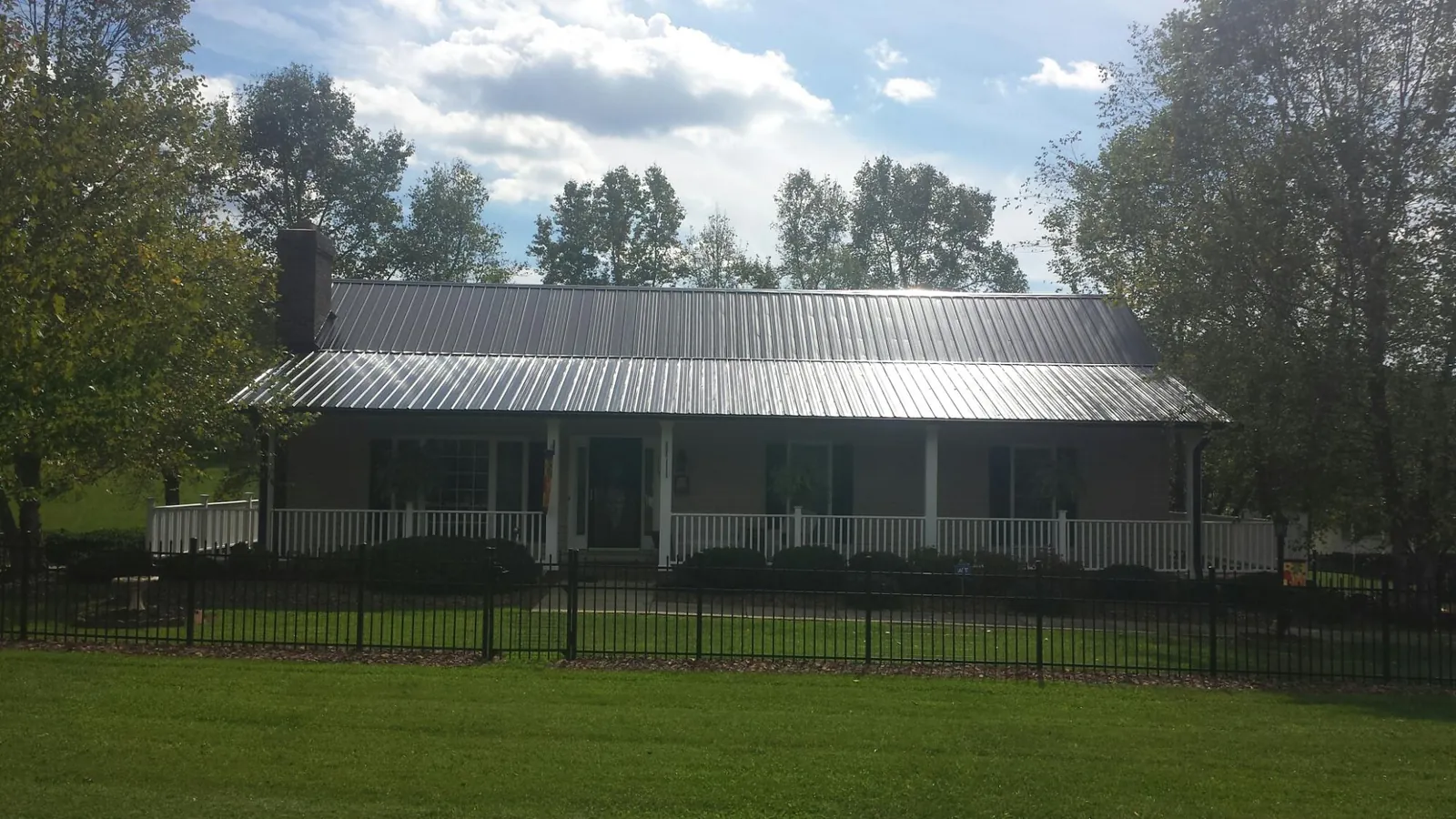 Gray metal roof on a brick ranch with a full width front porch — Gutter Guard Installation work by our crew in Canyonville