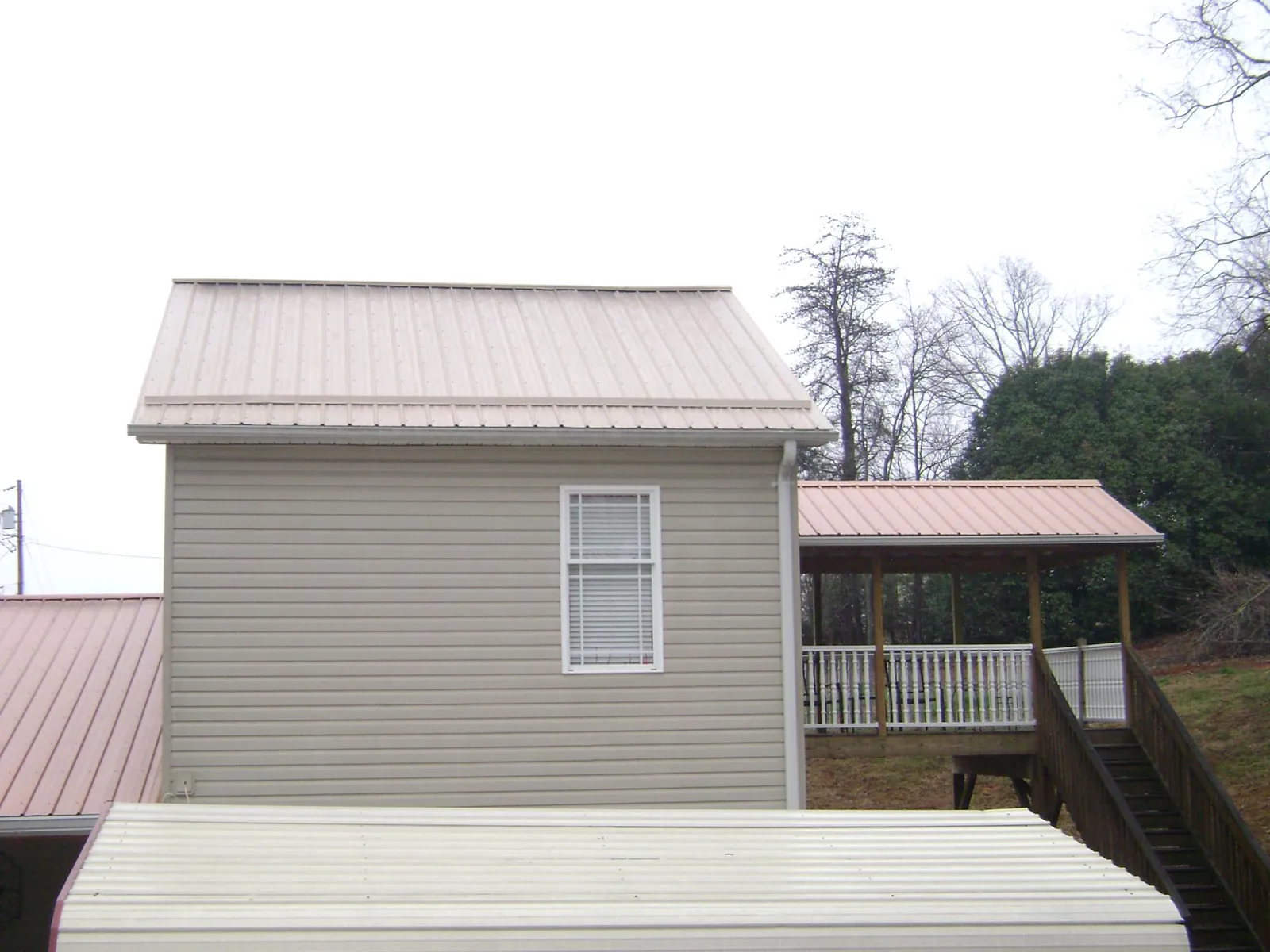 Tan metal roofs on a two story addition and attached porch, from a Roof Replacement job in Canyonville