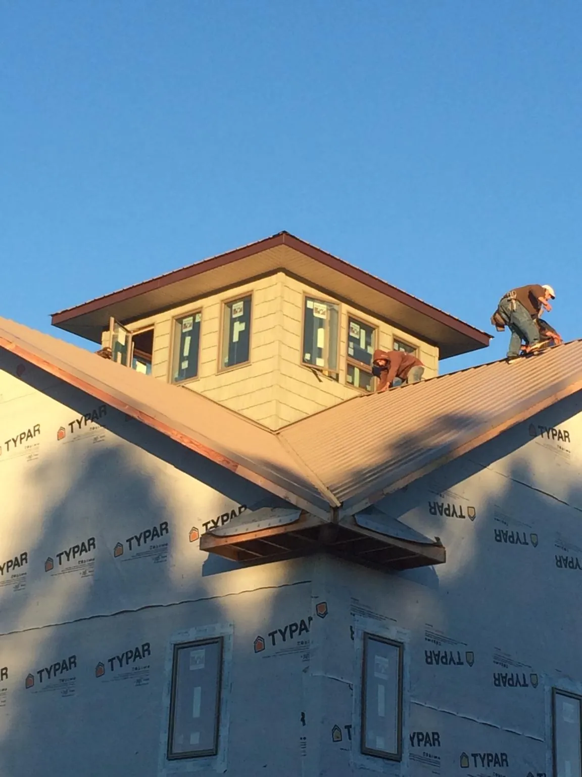 Roofers working around a rooftop cupola on a new metal roof at sunset — Roof Waterproofing in Canyonville by Roofing Brothers